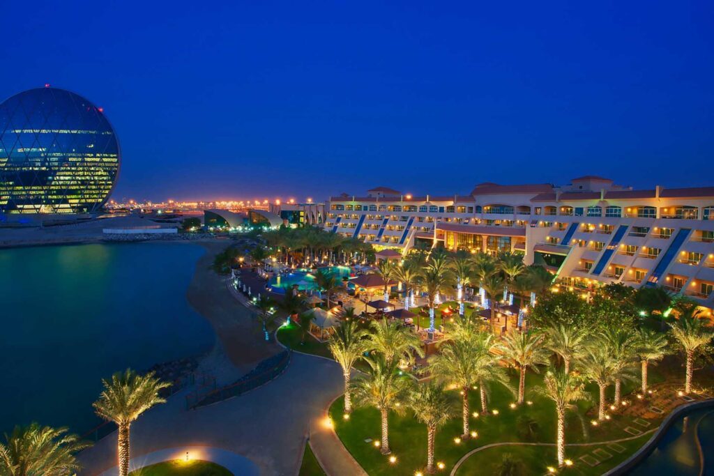 The low rise blocks and gardens of Al Raha Beach Resort along the channel