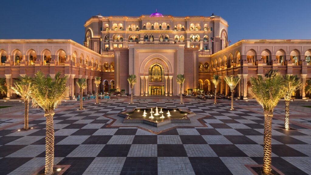 Emirates Palace Mandarin Oriental, Abu Dhabi illuminated at dusk, viewed across its grand entrance courtyard.