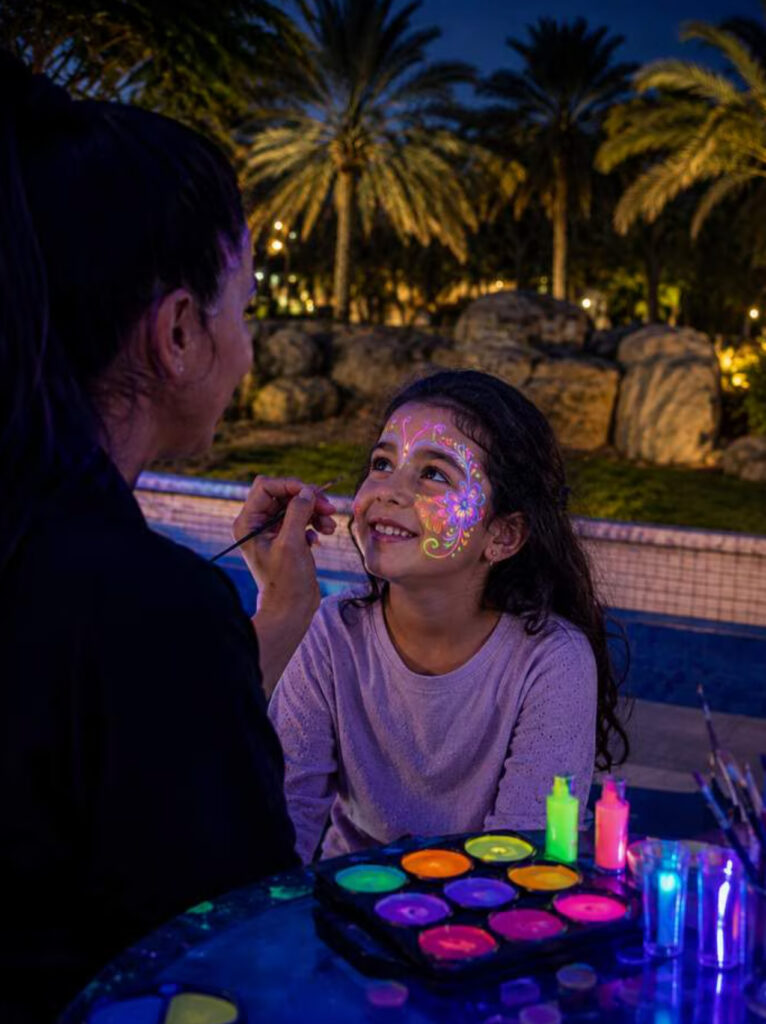 A child having a colourful nature-inspired design painted on her face during a glow-in-the-dark face-painting activity.